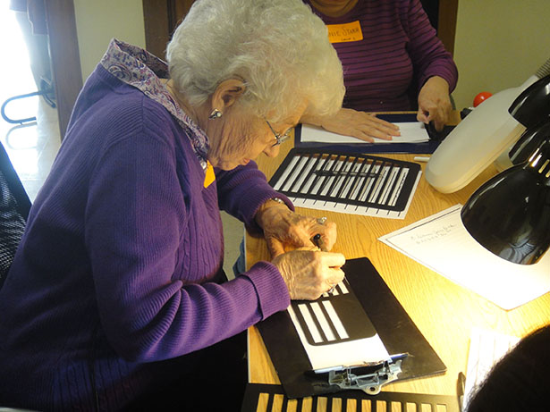 Eleanor Baker uses an envelop guide when practicing writing an address to help her write straight. Photo courtesy of the San Antonio Lighthouse for the Blind.
